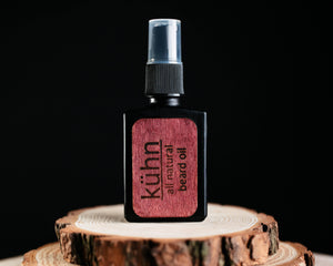 kühn beard oil sitting atop a piece of wood with a dark background and lit up front.